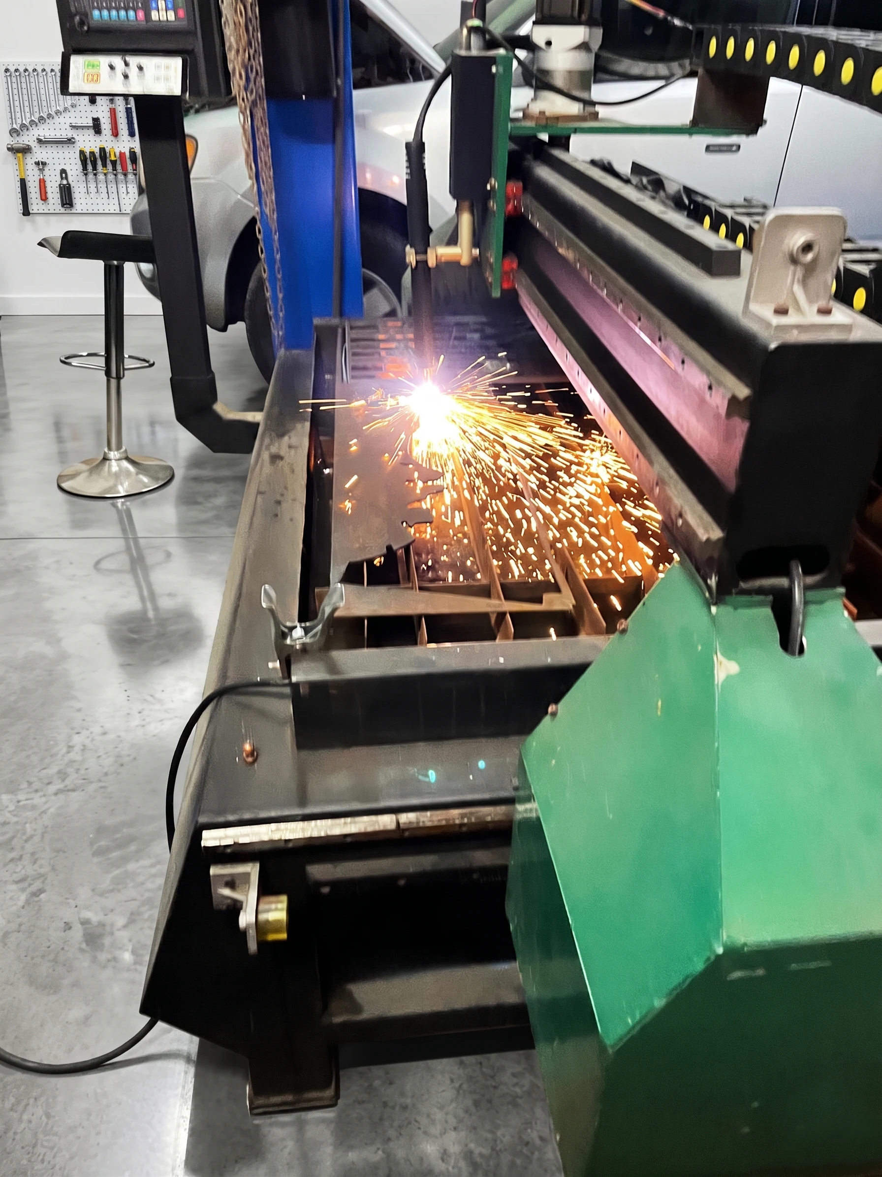 Máquina de plasma CNC cortando con una lluvia de chispas dentro del taller